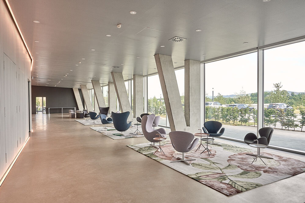 Eingangshalle mit Sesseln von Fritz Hansen und floralen Teppichen in gedeckten Farben