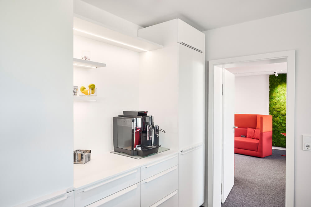 Büroküche mit weißen minimalistischen Schränken